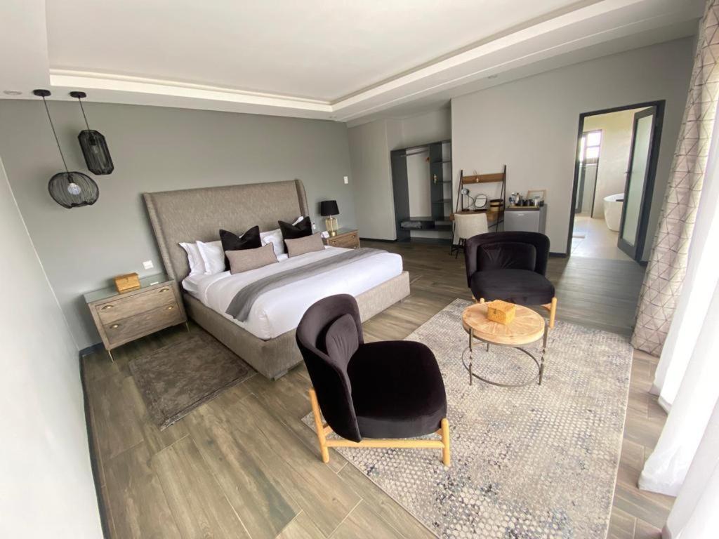 a bedroom with a bed and two chairs and a table at Exquisite premium Fulatha Suite - 2202 in Bulawayo