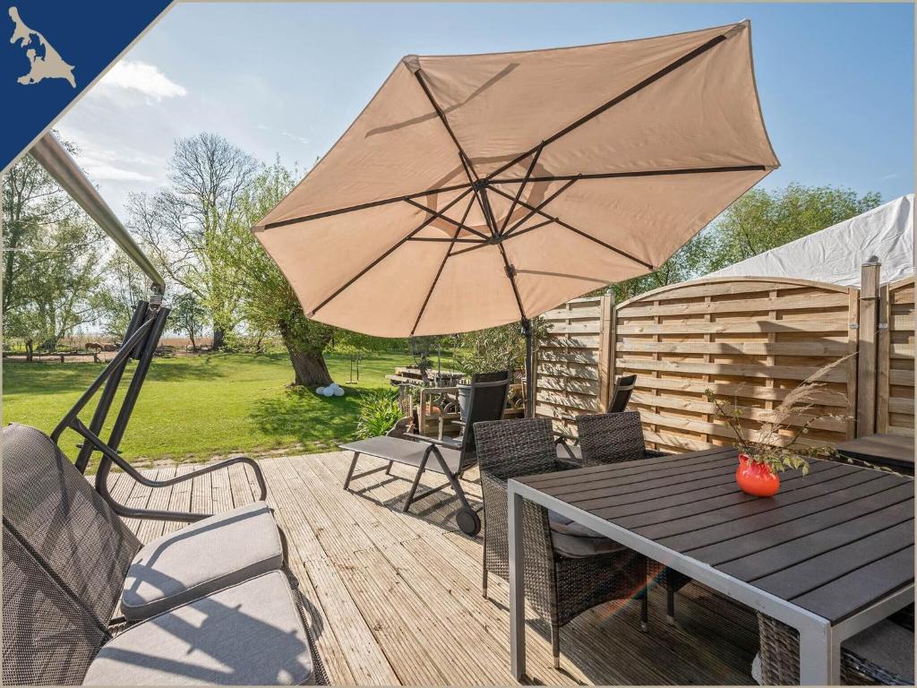 a wooden deck with a table and an umbrella at Ferienwohnung mit Kamin am Achterwasser in Lütow in Lütow