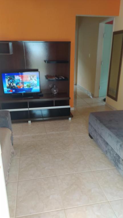 sala de estar con TV de pantalla plana y sofá en Acomodação vó Nilton, en Governador Celso Ramos