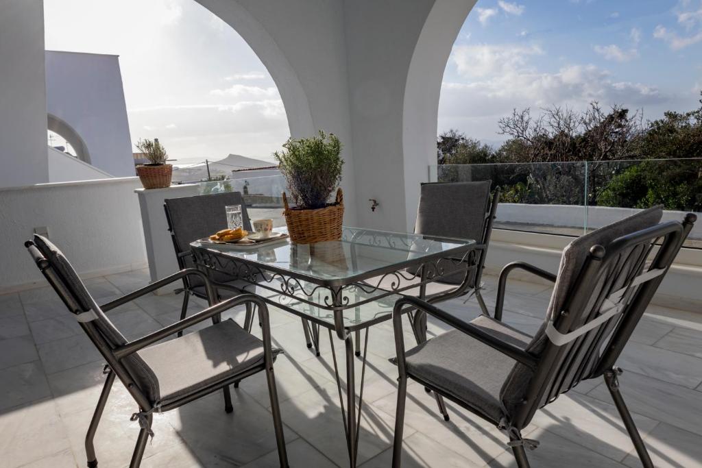 y balcón con mesa de cristal y sillas. en Αegean Εyes en Tinos Town