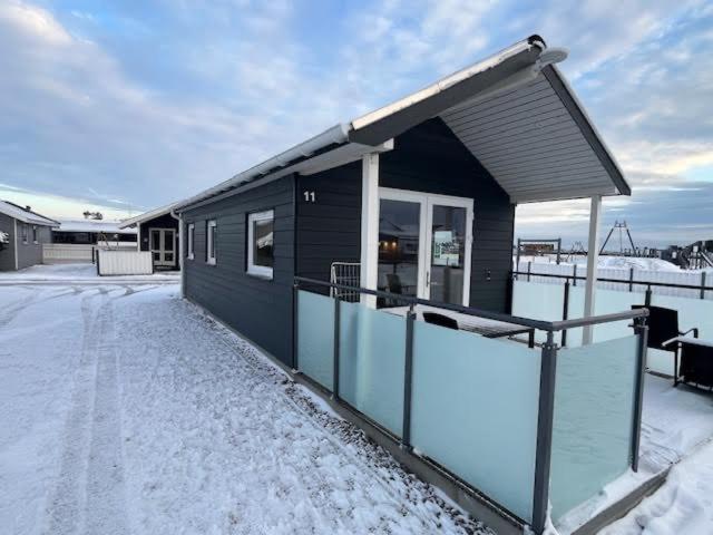 a black house with snow on the ground at Storebælt camping in Korsør