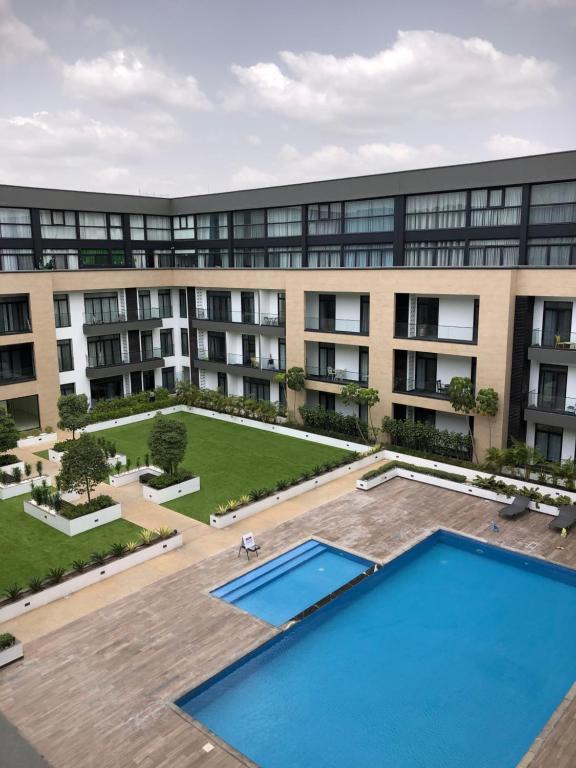 an apartment building with a large pool in front of it at Embasy Gardens by Rosy Apartments in Accra