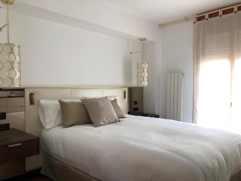 Un dormitorio con una gran cama blanca y una ventana en Quatrecantons Camprodon, en Camprodon