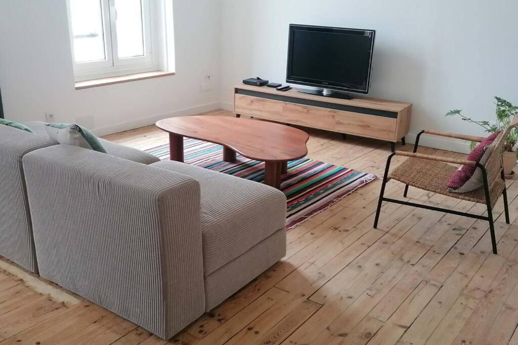 uma sala de estar com um sofá, uma mesa e uma televisão em Appart cœur de ville belle vue em Vichy