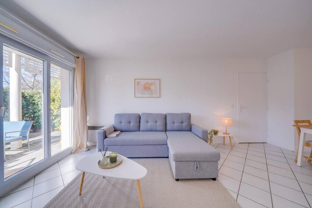- un salon avec un canapé bleu et une table dans l'établissement Charmant Appartement avec Jardin, à Pessac