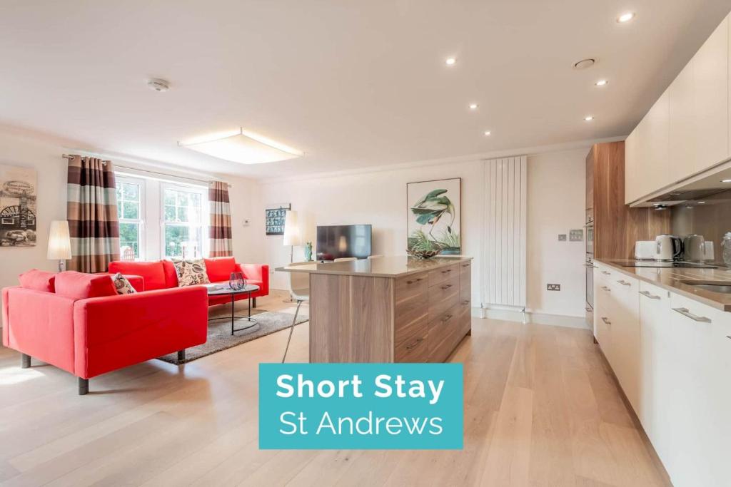 a kitchen and living room with red chairs and a red couch at Kinness House, Luxury Apartment with Parking in St. Andrews