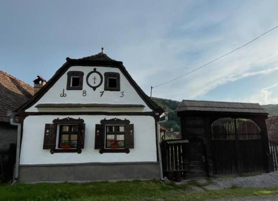 een klein huis met een klok erop bij Erdélyi parasztház in Veţca
