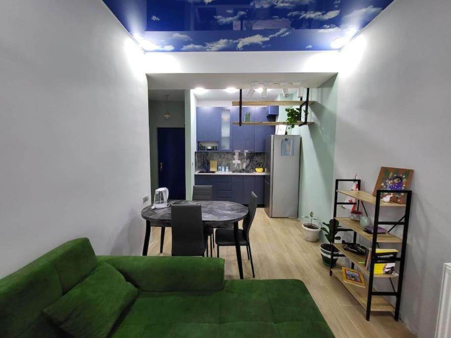 a living room with a green couch and a table at BlueVibe Apartment in Tbilisi City
