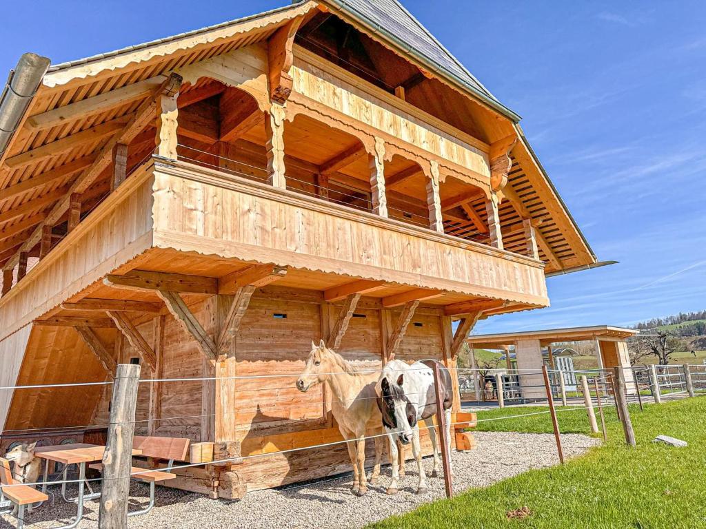 a cow standing in front of a wooden building at Ferienhaus Spycher im Emmental in Lützelflüh