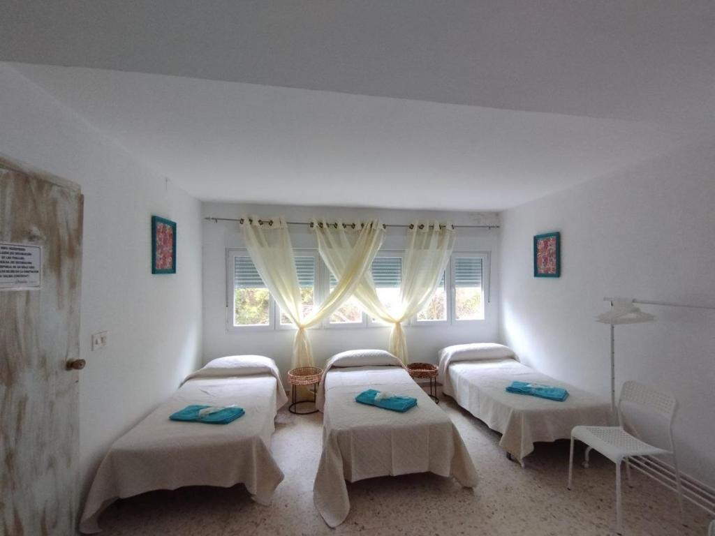 a room with three beds and a window at Chalet Lanzada in Sanxenxo