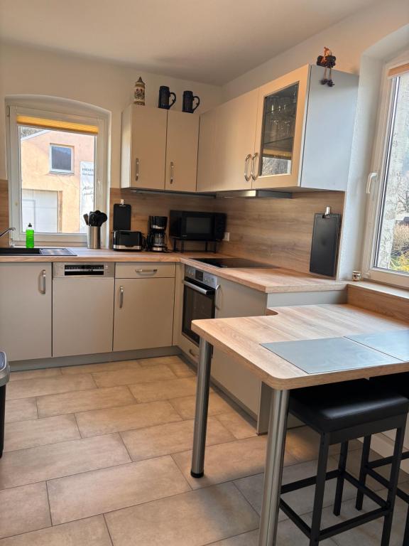a kitchen with white cabinets and a wooden table at Ferienwohnung Freital-City in Freital