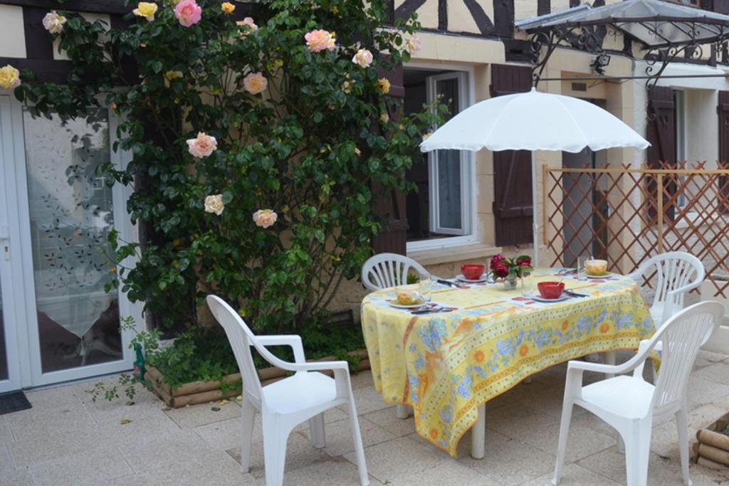 uma mesa e cadeiras com um guarda-sol e flores em Gtes Aux Portes de lEure Les Coquelicots em Vernon