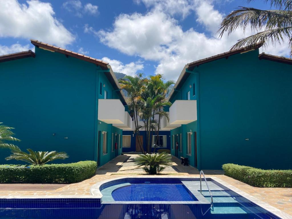 a pool in front of a building with a blue wall at Mar e Lua Flats - Maresias in Maresias