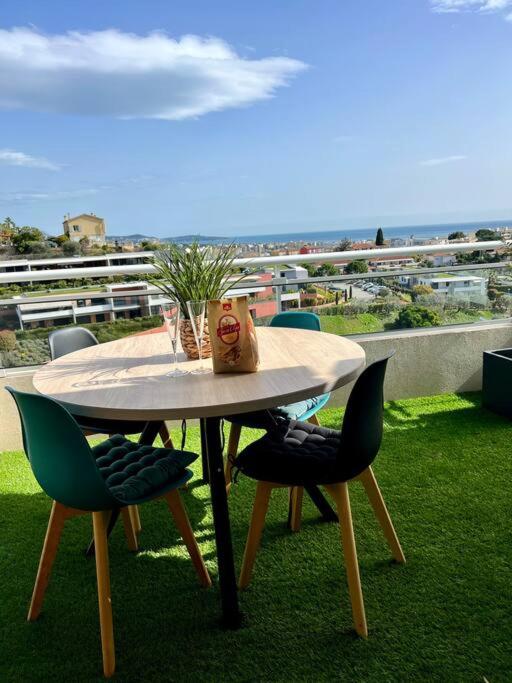 une table avec des chaises et un vase posé dessus dans l'établissement Appartement vue mer avec garage, à Saint-Laurent-du-Var