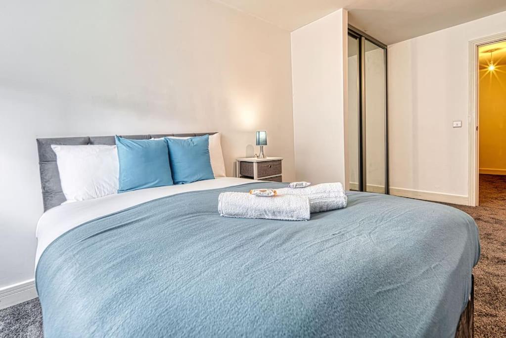 a bedroom with a large bed with blue pillows at Guest Homes - Cutlass Court in Birmingham