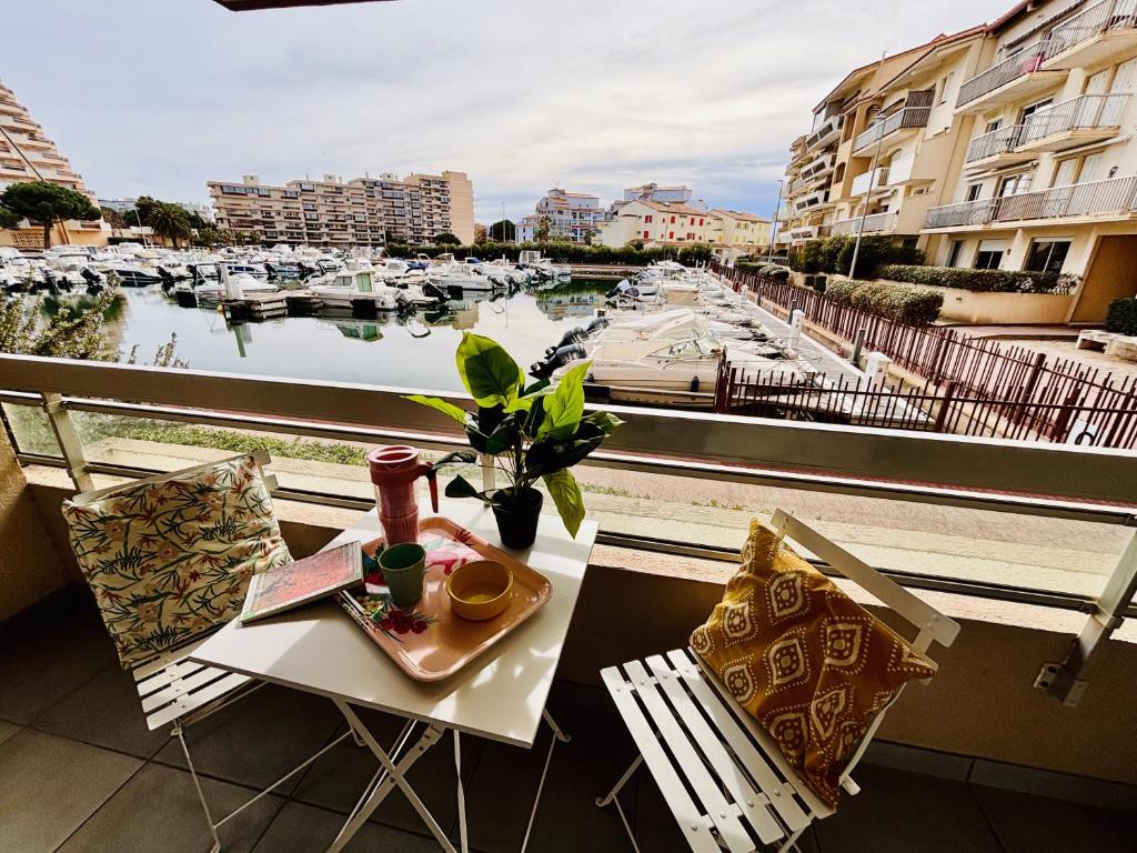 een tafel en stoelen op een balkon met uitzicht op een jachthaven bij Magnifique T2 au calme avec une superbe vue sur le port in Canet-en-Roussillon