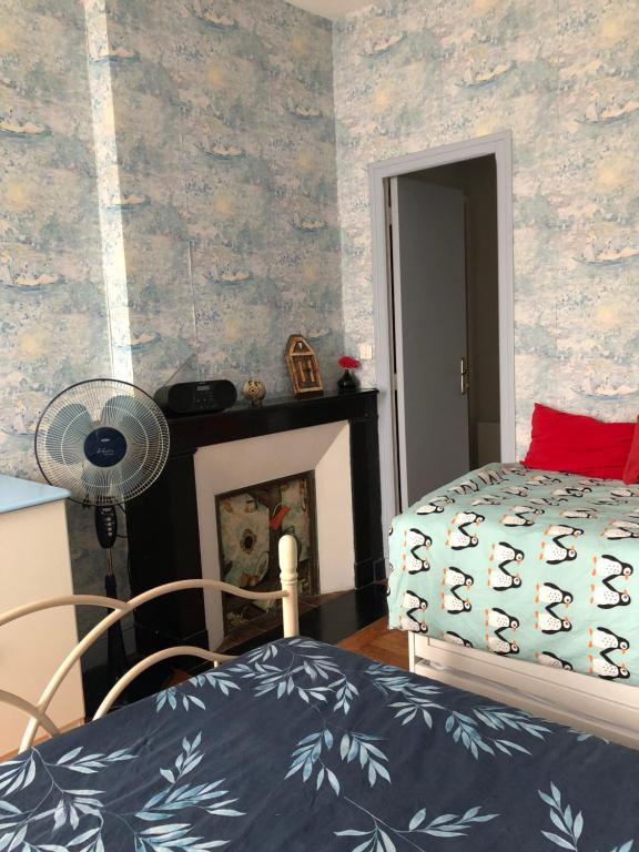 1 dormitorio con 1 cama, chimenea y ventilador en 77 Bleu, en Balleroy