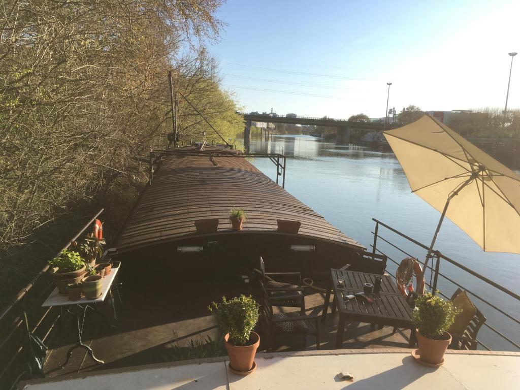una barca sull'acqua con tavolo e ombrellone di Péniche logement d'exception sur la Seine Spécial JEUX OLYMPIQUES a LʼÎle-Saint-Denis