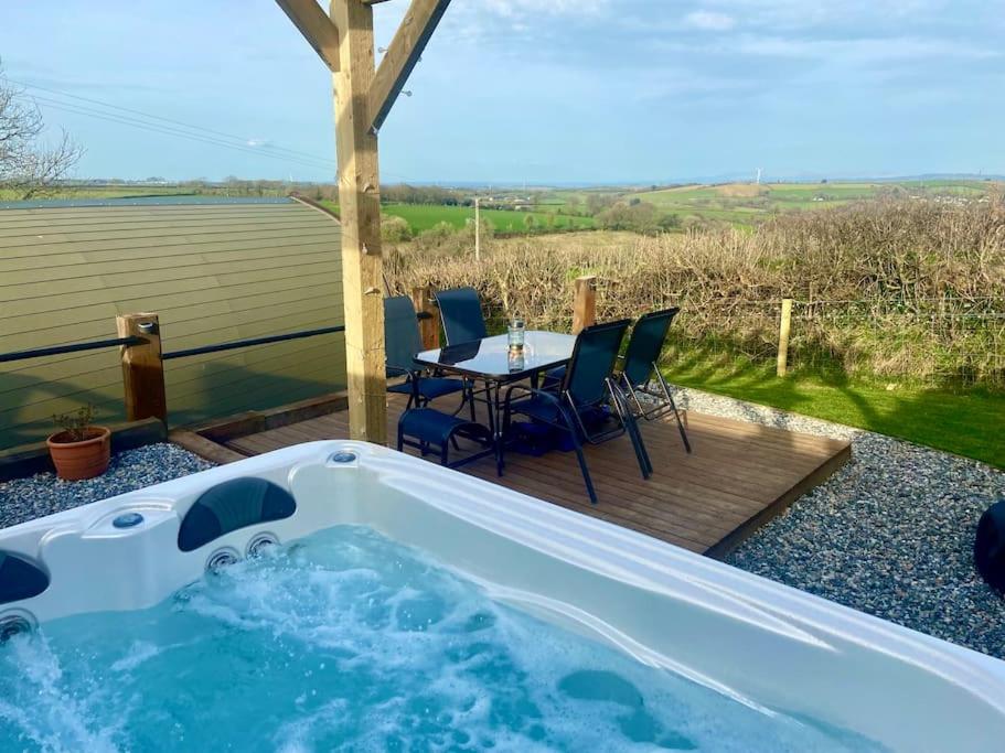 uma banheira de hidromassagem num deque com uma mesa e cadeiras em Secluded Luxury Pod with Hot Tub em Launceston