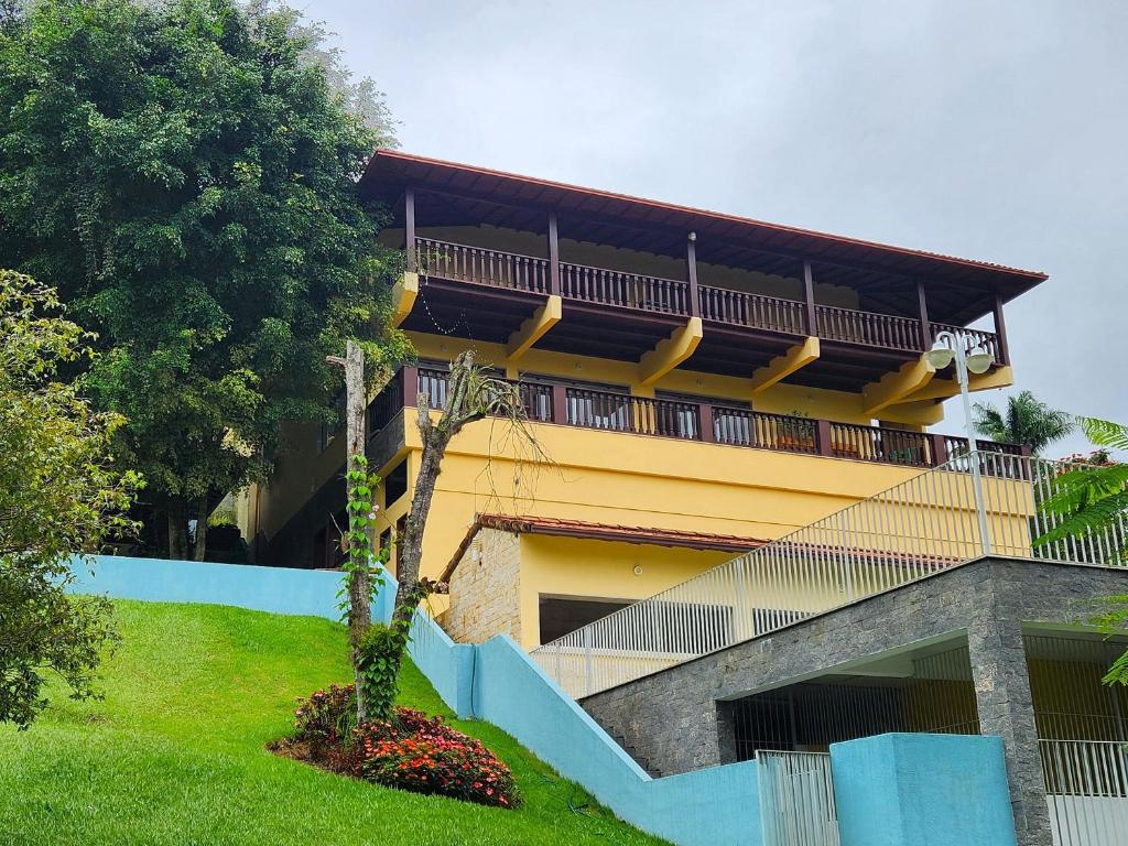 um edifício amarelo com uma varanda ao lado em Casa Feliz no Jardim Itaipava, 7 quartos, conforto em Itaipava