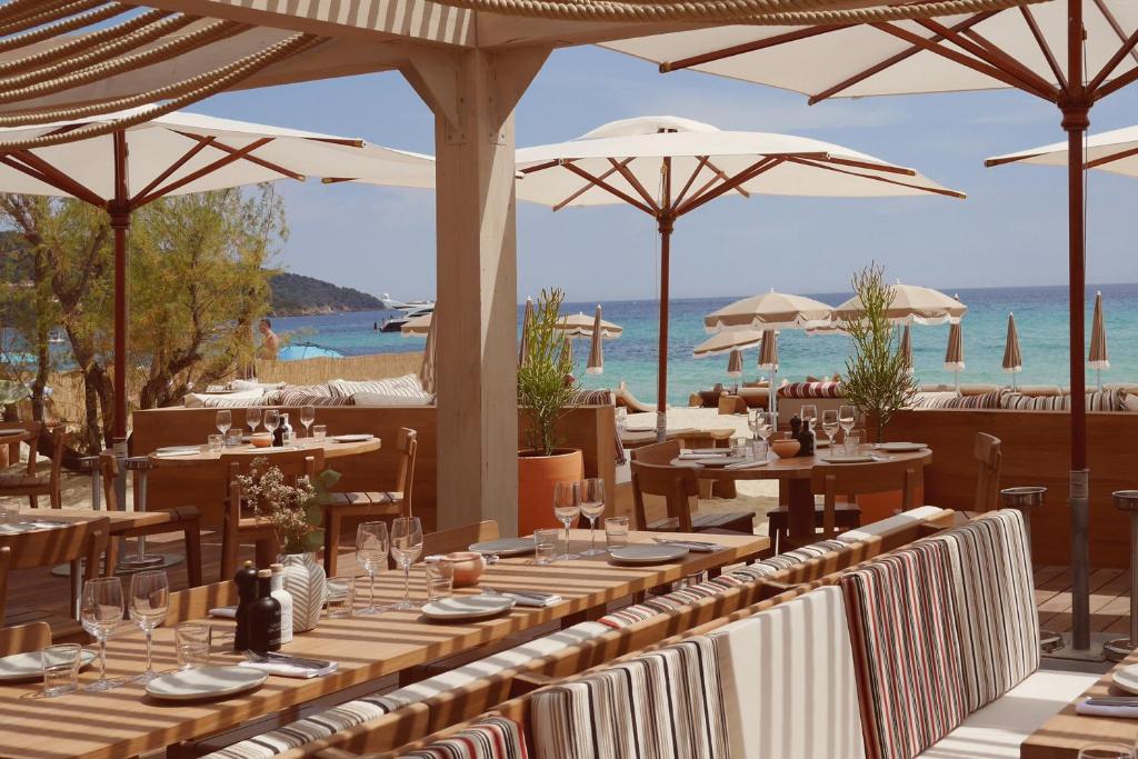 a restaurant with tables and umbrellas on the beach at Toison D'or in Saint-Tropez