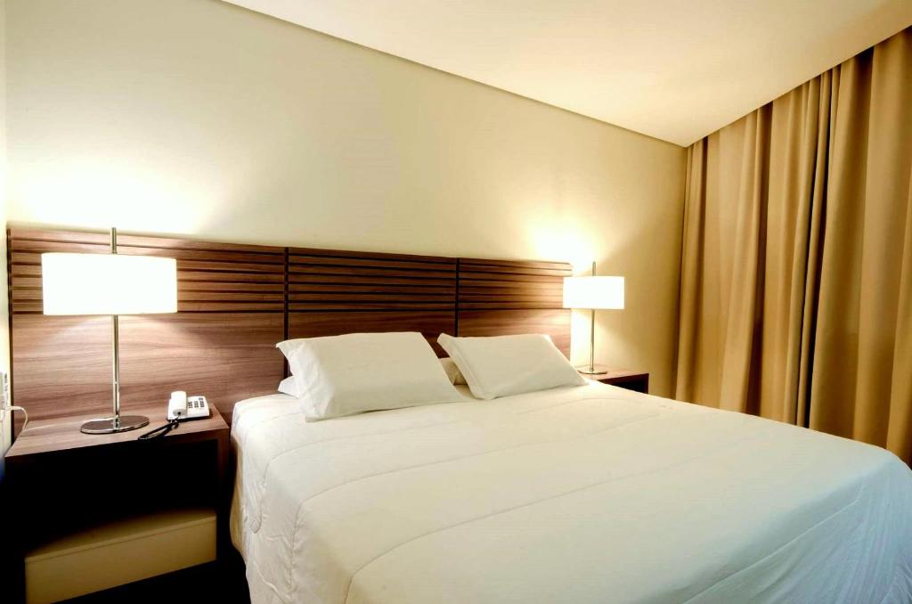 a bedroom with a large white bed and two lamps at Umbu Hotel Porto Alegre - Centro Histórico - Prox Aeroporto 15min in Porto Alegre