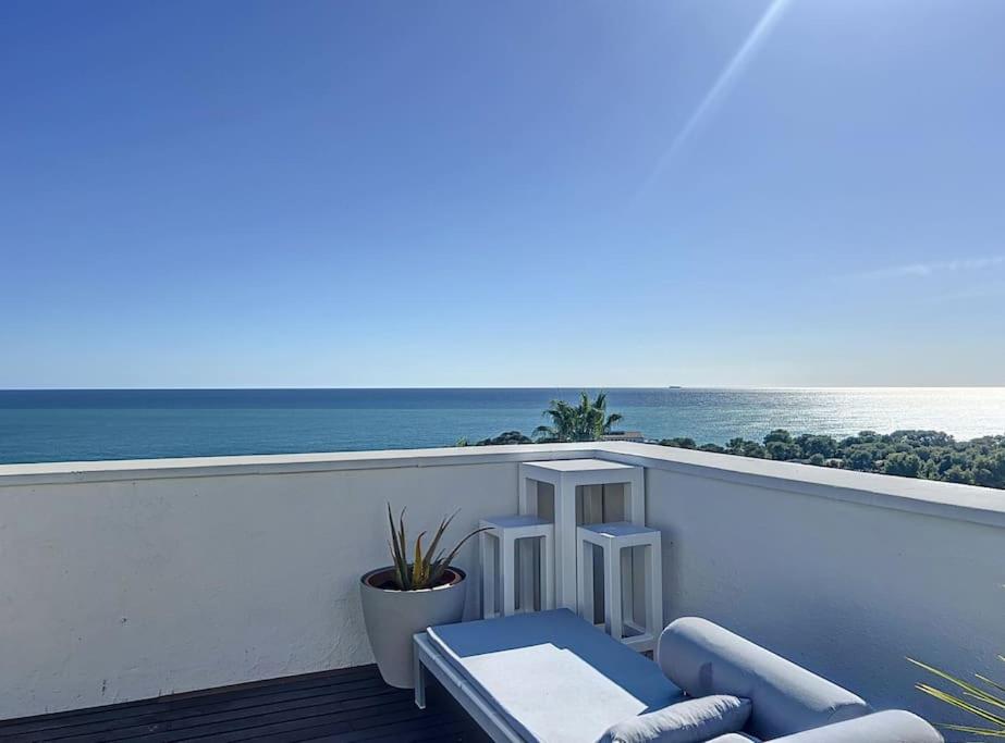uma varanda com uma cadeira, uma mesa e o oceano em Duplex vistas mar con piscina em Sant Pere de Ribes