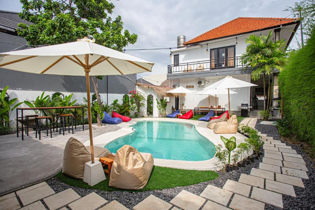 a swimming pool with an umbrella and chairs and a table at What The Duck Backpackers in Canggu