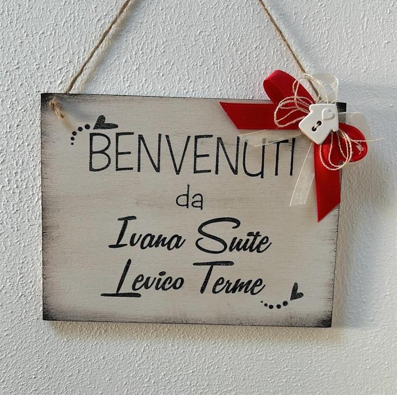 a sign hanging on a wall with a red bow at Ivana-suite CIPAT 022104-AT-013433 in Levico Terme