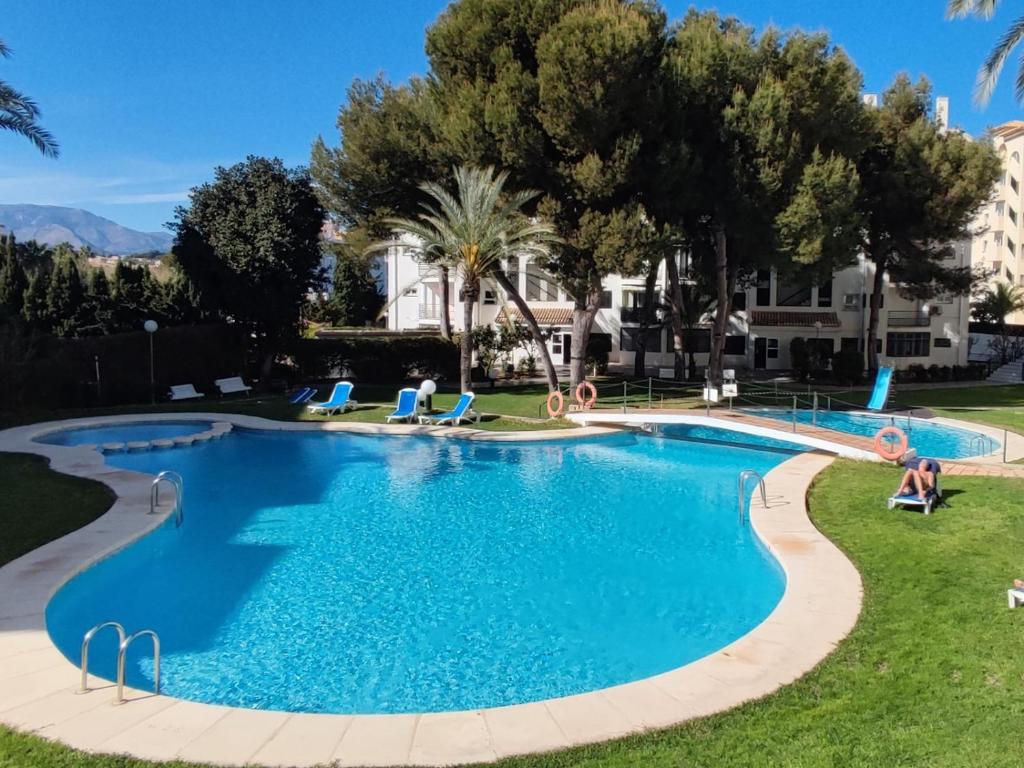 een zwembad in een resort met palmbomen bij Casa Capitolio - Albir in Albir