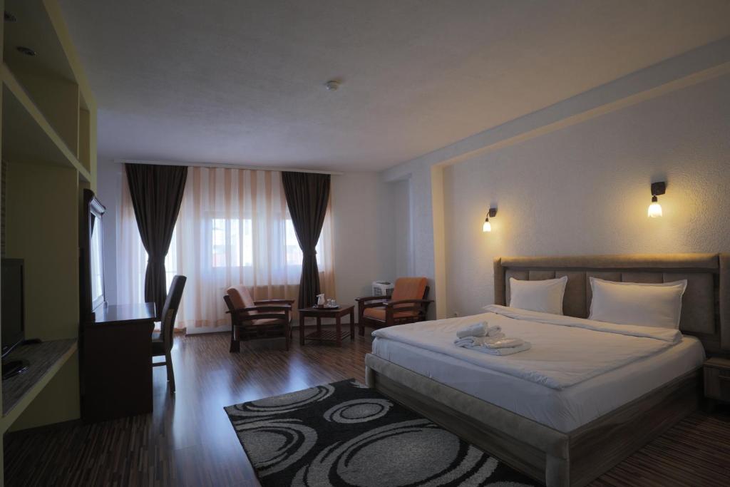 a hotel room with a bed and a table and chairs at Hotel Denis in Pristina