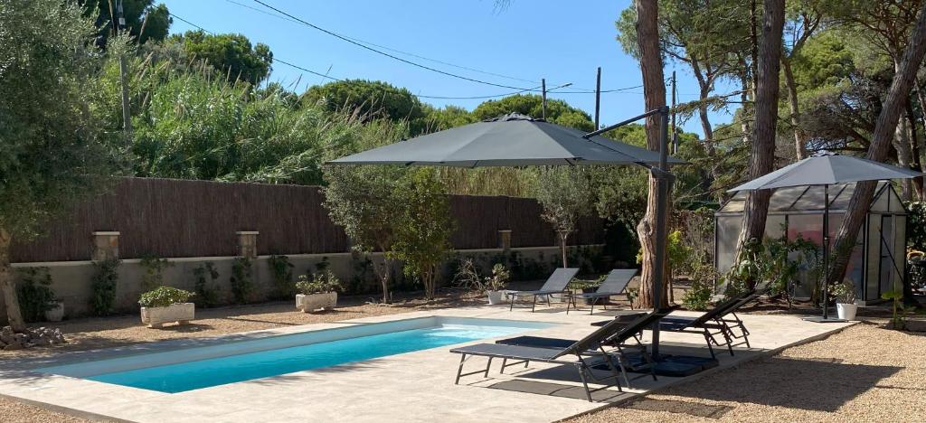 a swimming pool with two chairs and an umbrella at Fantastica casa con piscina a 5 min a pie del mar - Sorramar in Gavà
