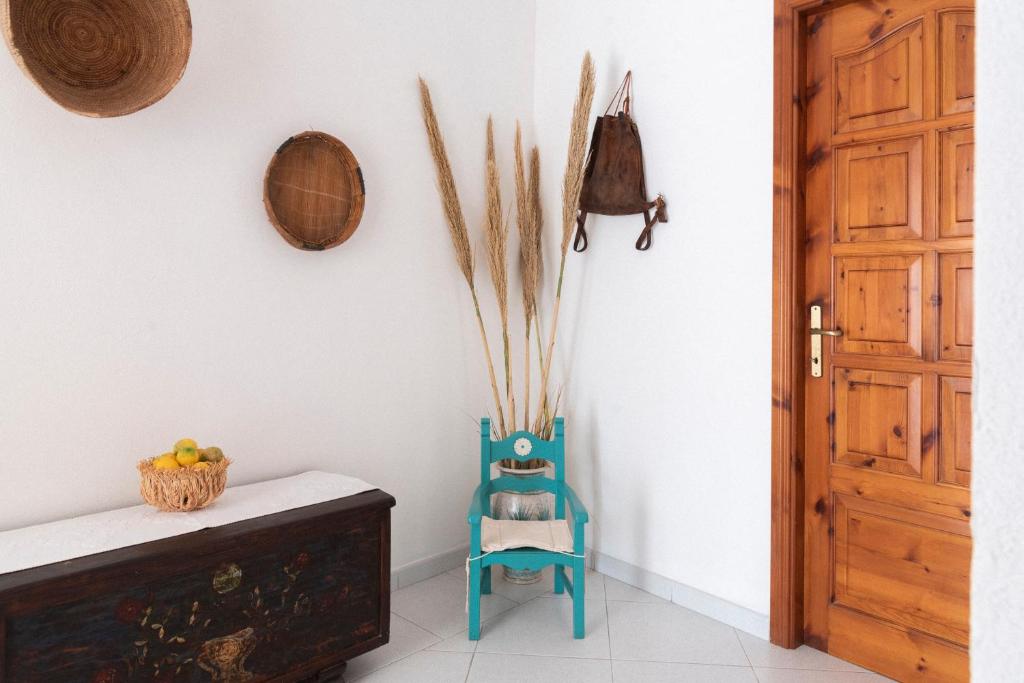 een kamer met een blauwe stoel en een houten deur bij Casa Duesse in Orosei