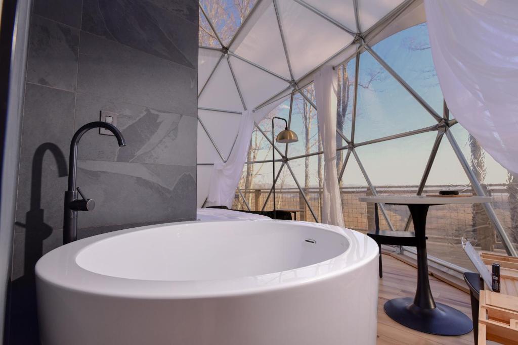 a bathroom with a tub in a tent with a table at Tranquility Luxe Dome - Hot Tub & Luxury Amenities in Swiss