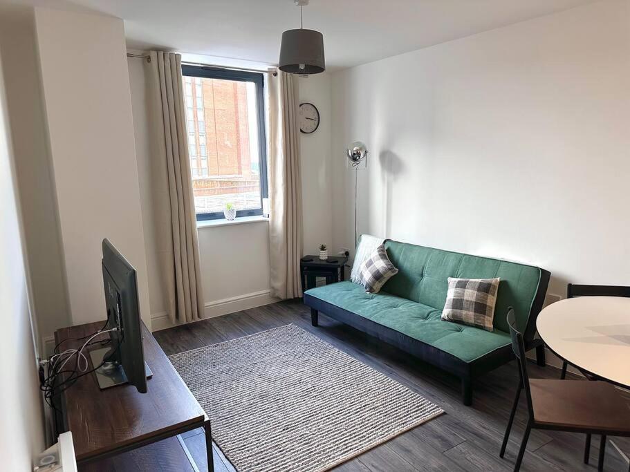 a living room with a green couch and a table at Queens House City Centre Apartments in Sheffield