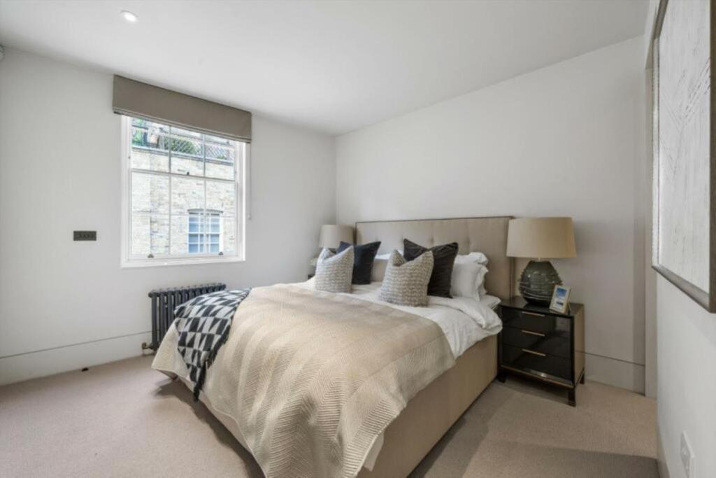 um quarto com uma cama grande e uma janela em LARGE PENTHOUSE MAYFAIR SLEEPS UP TO 12 em Londres