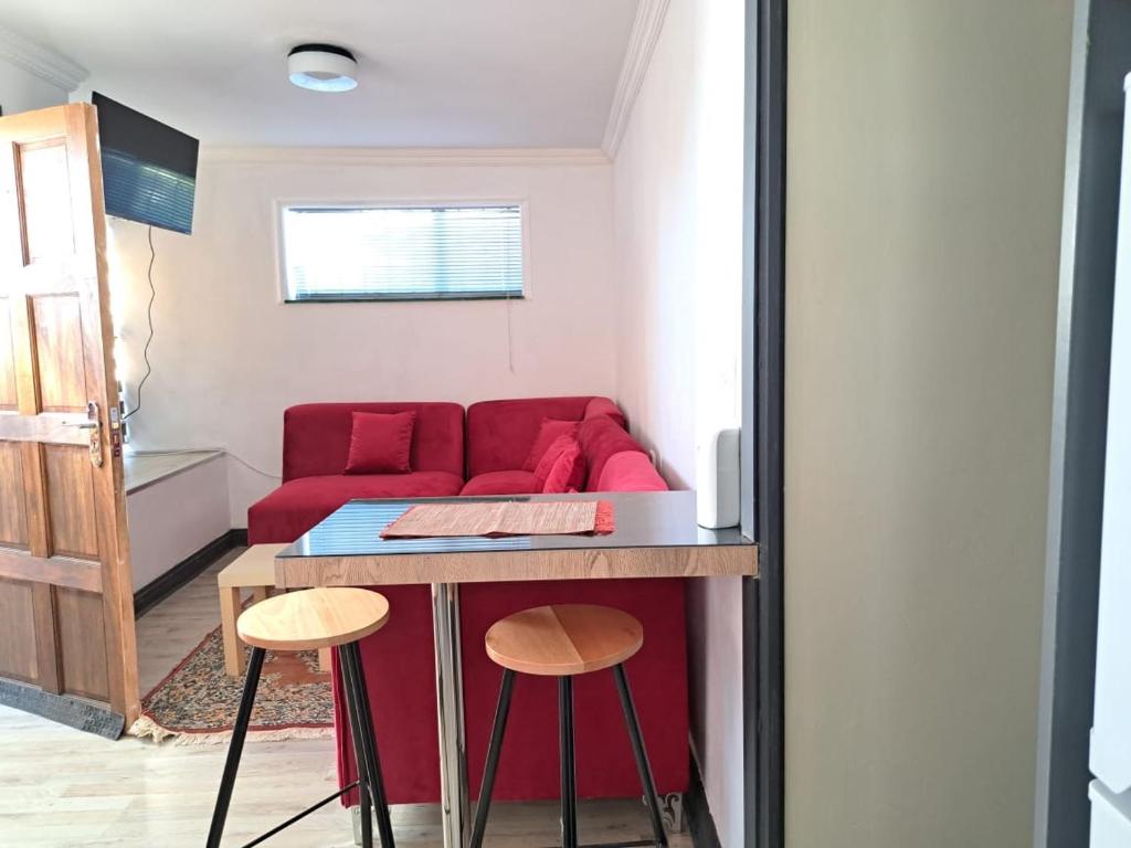 een woonkamer met een rode bank en een tafel bij Muhlemoholo Guest House in Maseru
