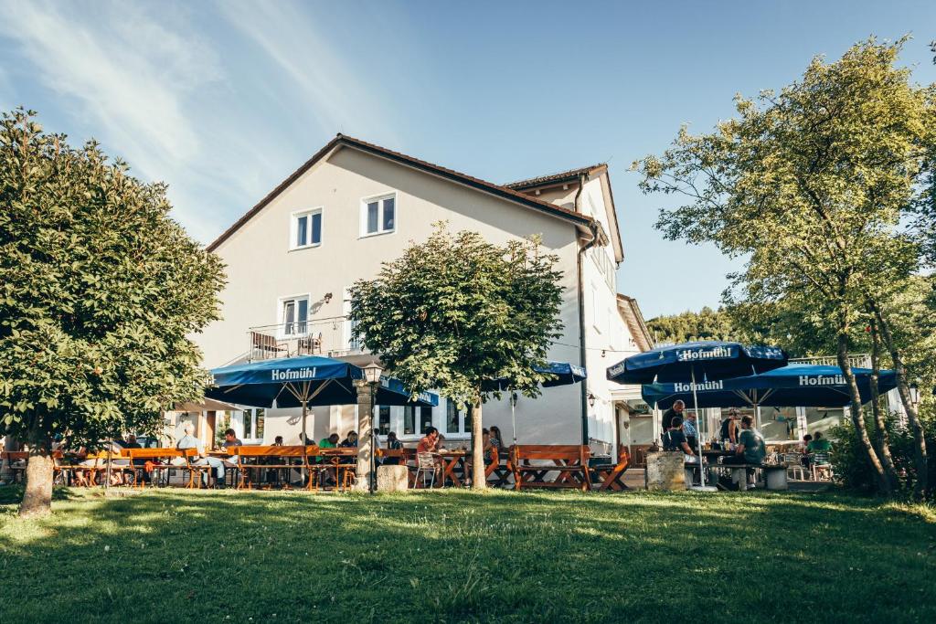 ein Restaurant mit Tischen und Sonnenschirmen vor einem Gebäude in der Unterkunft Hirschenwirt in Eichstätt