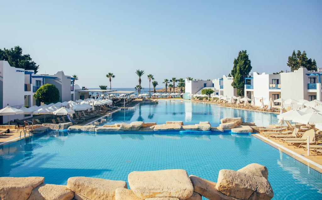 a large pool with chairs and umbrellas at a resort at Atlantica Callisto in Ayia Napa