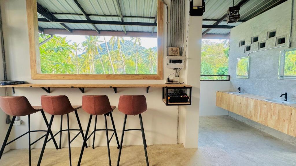 un bar con taburetes en una habitación con ventana en Koh Tao Silver Na’s Hostel en Ko Tao