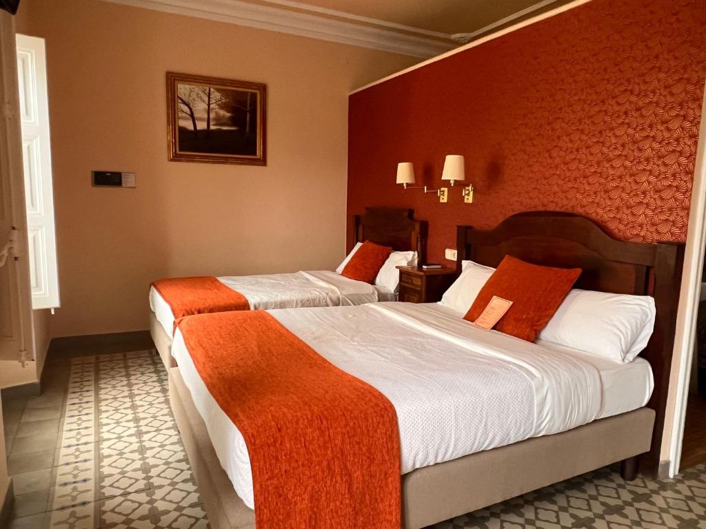 2 camas en una habitación de hotel con paredes rojas en Hotel Noucentista, en Sitges