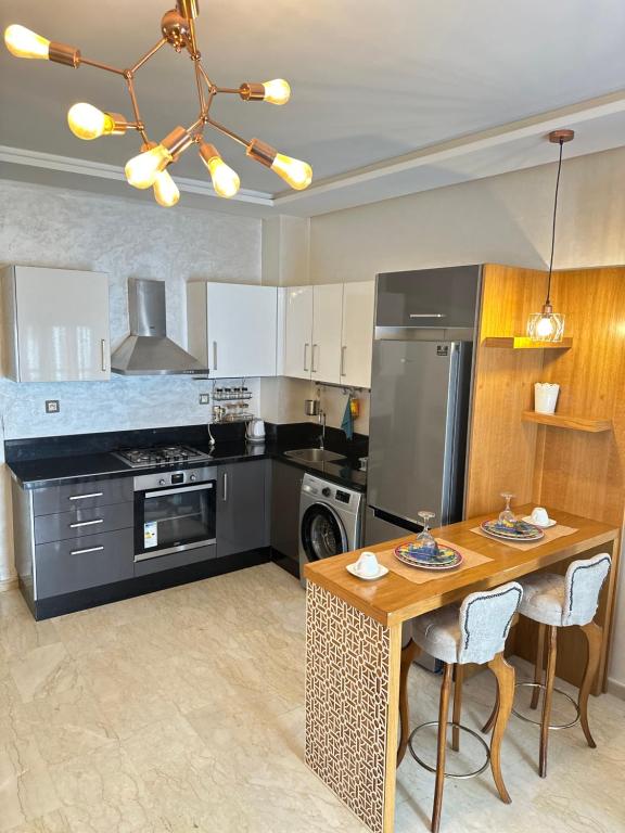 a kitchen with a table and a stove and refrigerator at Appartement confortable et pas cher au parc in Mohammedia