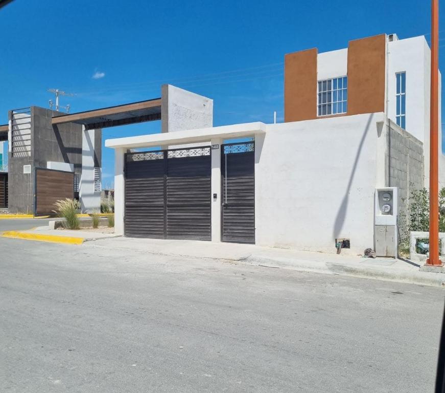 un bâtiment blanc avec deux portes de garage dans une rue dans l'établissement Casa Amistad, à Ciudad Acuña