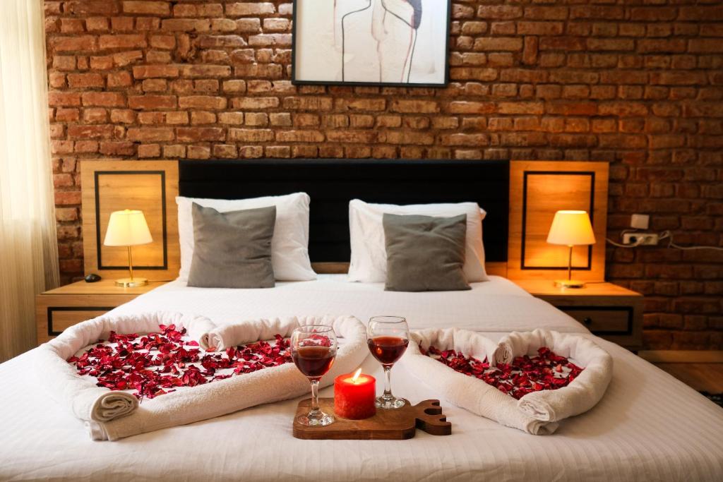 a bed with two heart shaped pillows and two glasses of wine at Taksim Nikea Suites 80 in Istanbul