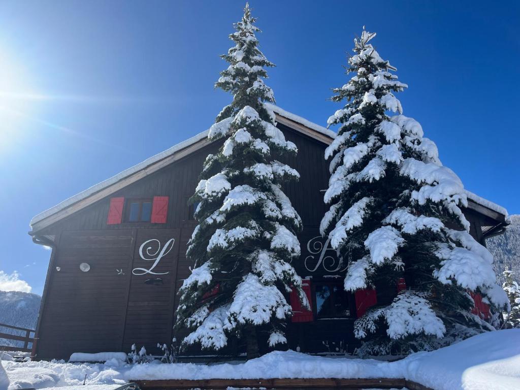 zwei schneebedeckte Bäume vor einem Gebäude in der Unterkunft Chalet l'Aigle bleu in Uvernet