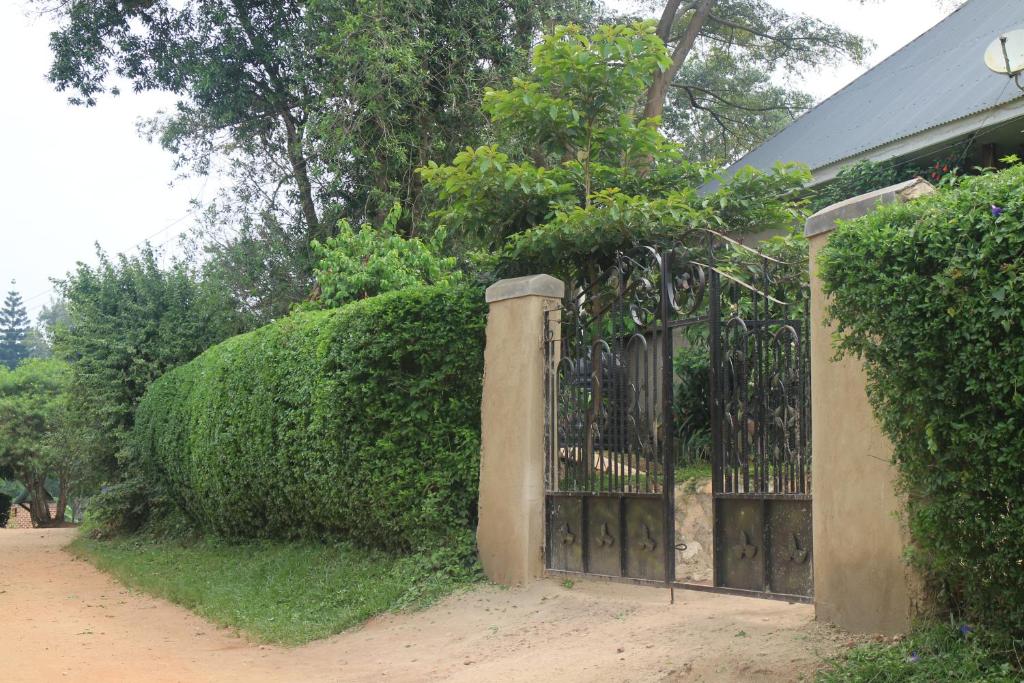 une porte devant une haie avec une maison dans l'établissement Kibale Eco-Home, à Bigodi