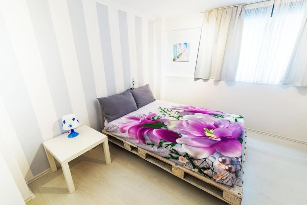 2 Bedrooms Apartment close to metro Dafni in Athens في أثينا: غرفة نوم مع سرير وبطانية زهرة أرجوانية