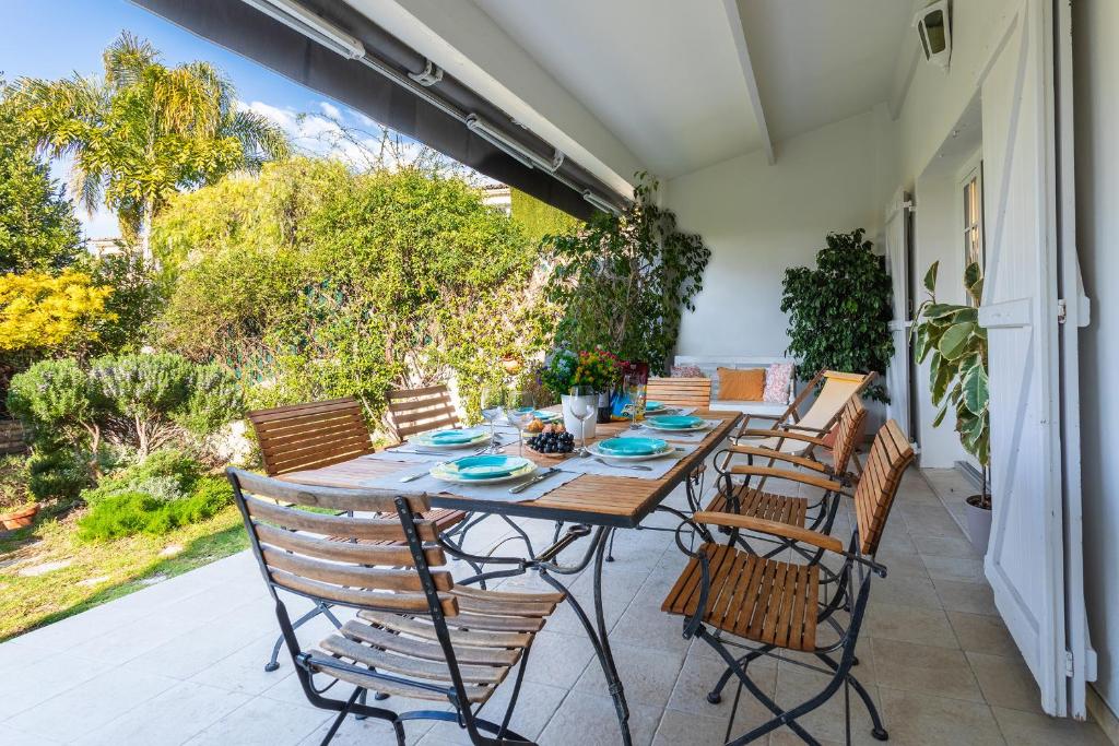 un patio avec une table et des chaises en bois dans l'établissement MAS DE GAIRAUT VI4395 By Riviera Holiday Homes, à Nice