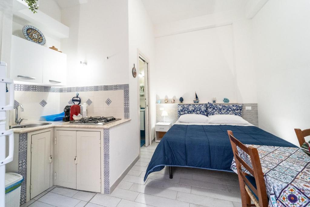 a white room with a bed and a kitchen at Affittacamere Cecilia in Castellammare del Golfo
