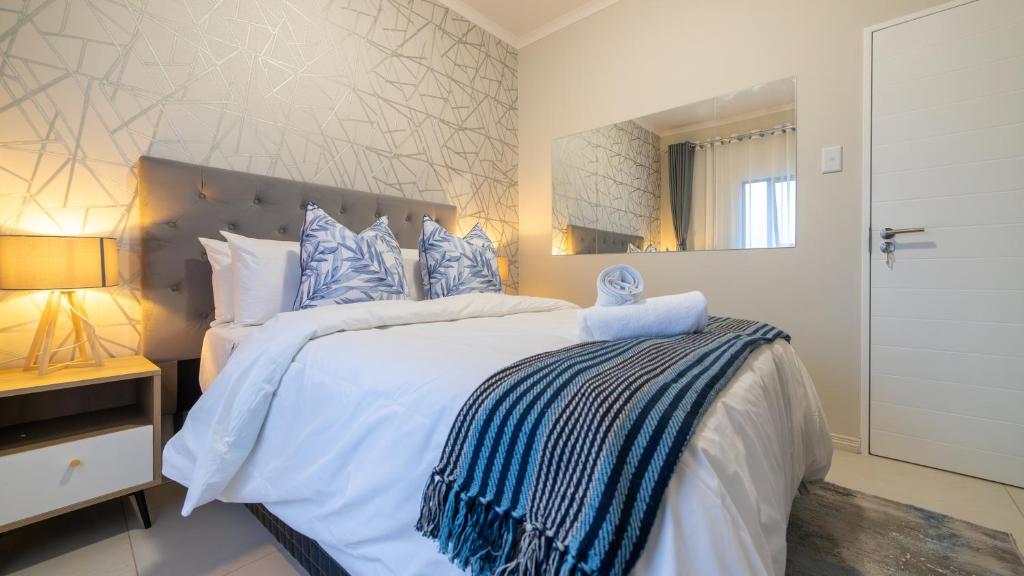 1 dormitorio con 1 cama blanca grande con almohadas azules en Chic Modern Midrand Escape en Midrand